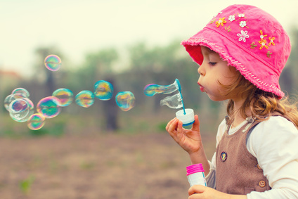 Little girl playing with soap bubbles